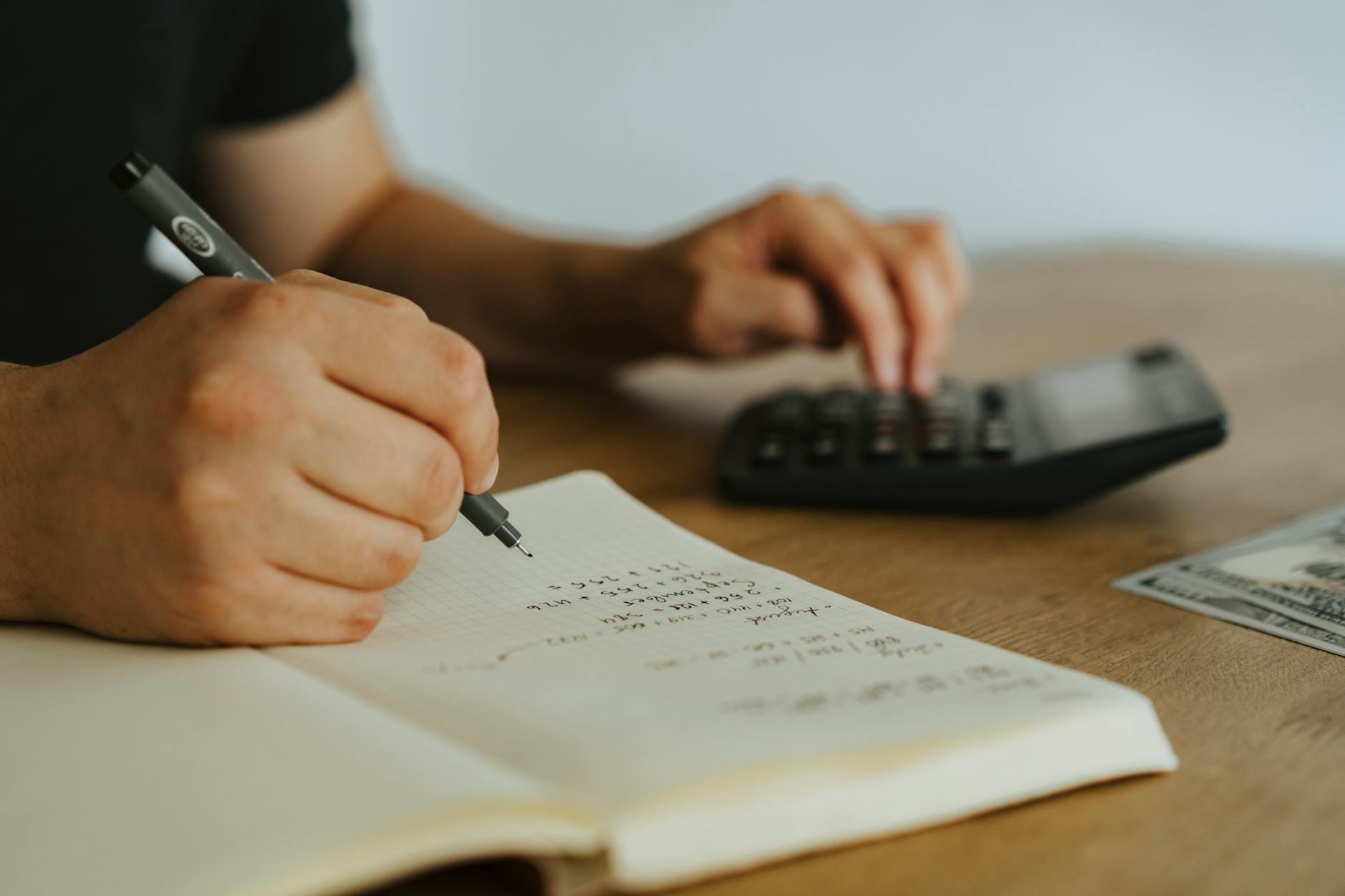 a person writing on white notebook
